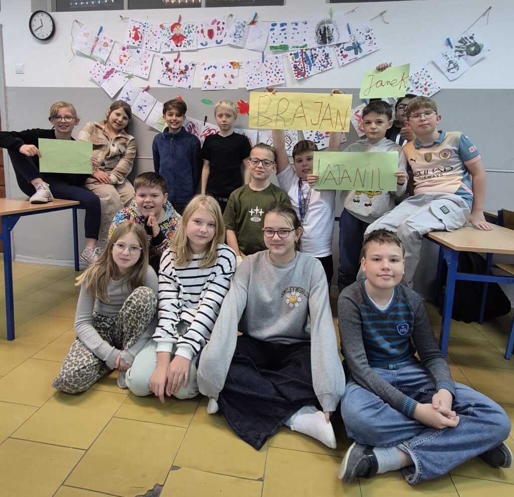 Uczniowie na zdjęciu grupowym na tle swoich prac