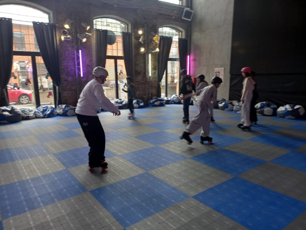 Dzieci jeżdżą na wrotkach. Mają kaski.