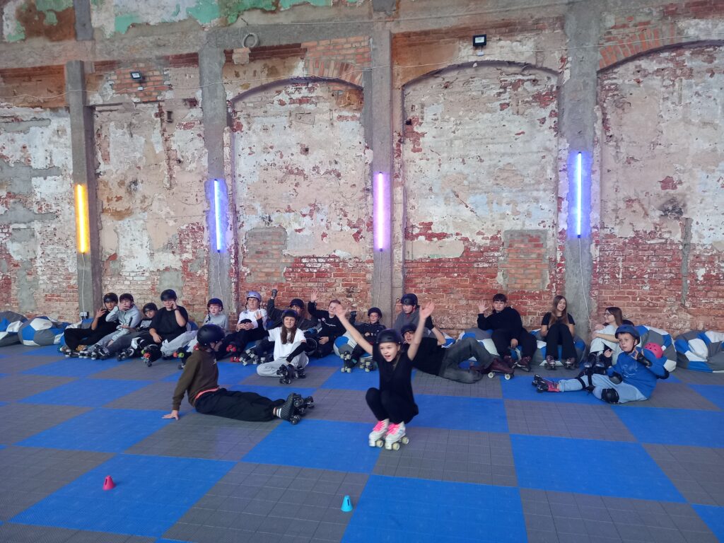 Dzieci odpoczywają po jeździe siedząc na podłodze. 