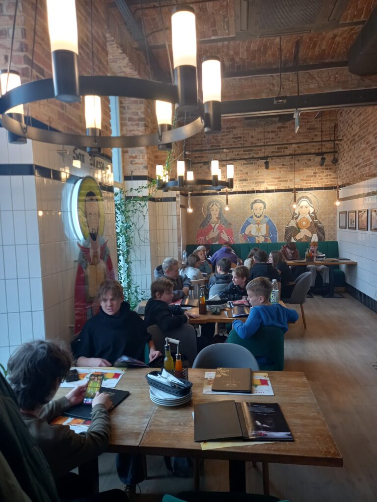 dzieci siedzą przy stolikach i czekają na jedzenie. 