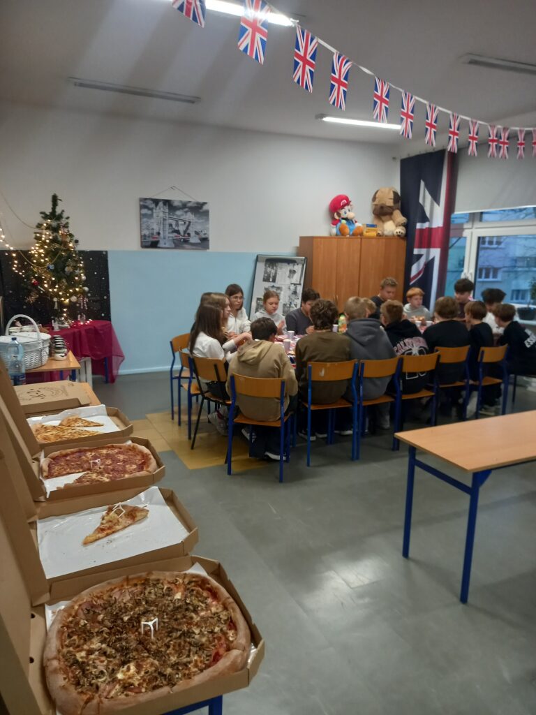 na pierwszym planie widać pizze, w oddali uczniowie siedzą w ławkach.