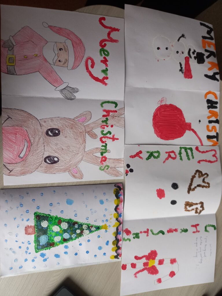 świąteczne kartki wykonane przez dzieci, renifery, mikołaje, napisy po angielsku.