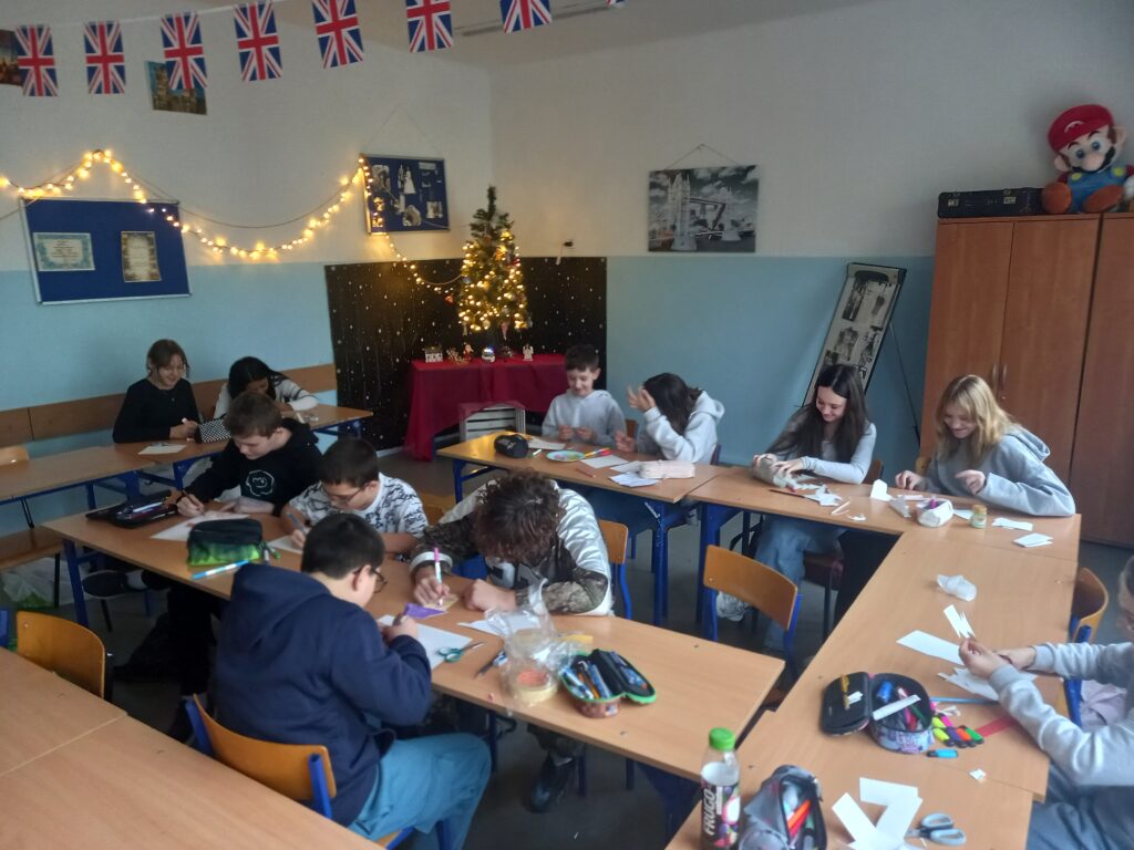 zdjęcie dzieci siedzących w ławkach i wykonujących kolorowe kartki świąteczne