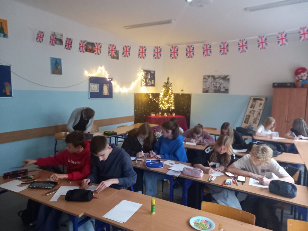 zdjęcie dzieci siedzących w ławkach i wykonujących kolorowe kartki świąteczne