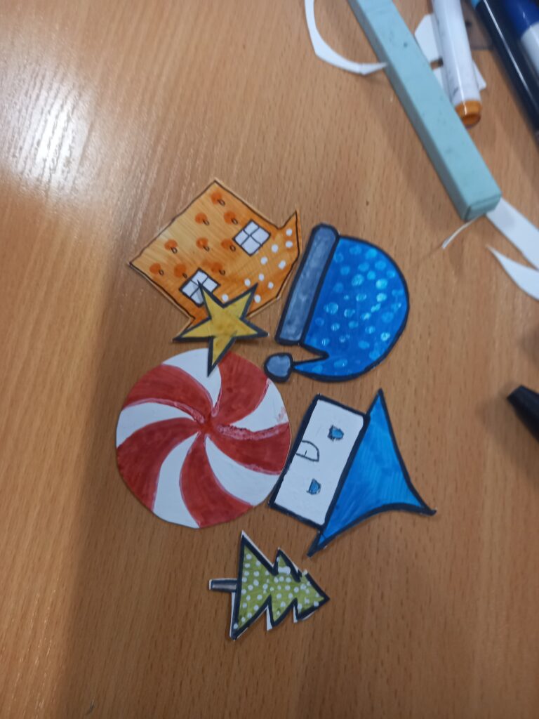 namalowane i wycięte kolorowe domki, piłka choinka gwiazdka i czapka niebieska.