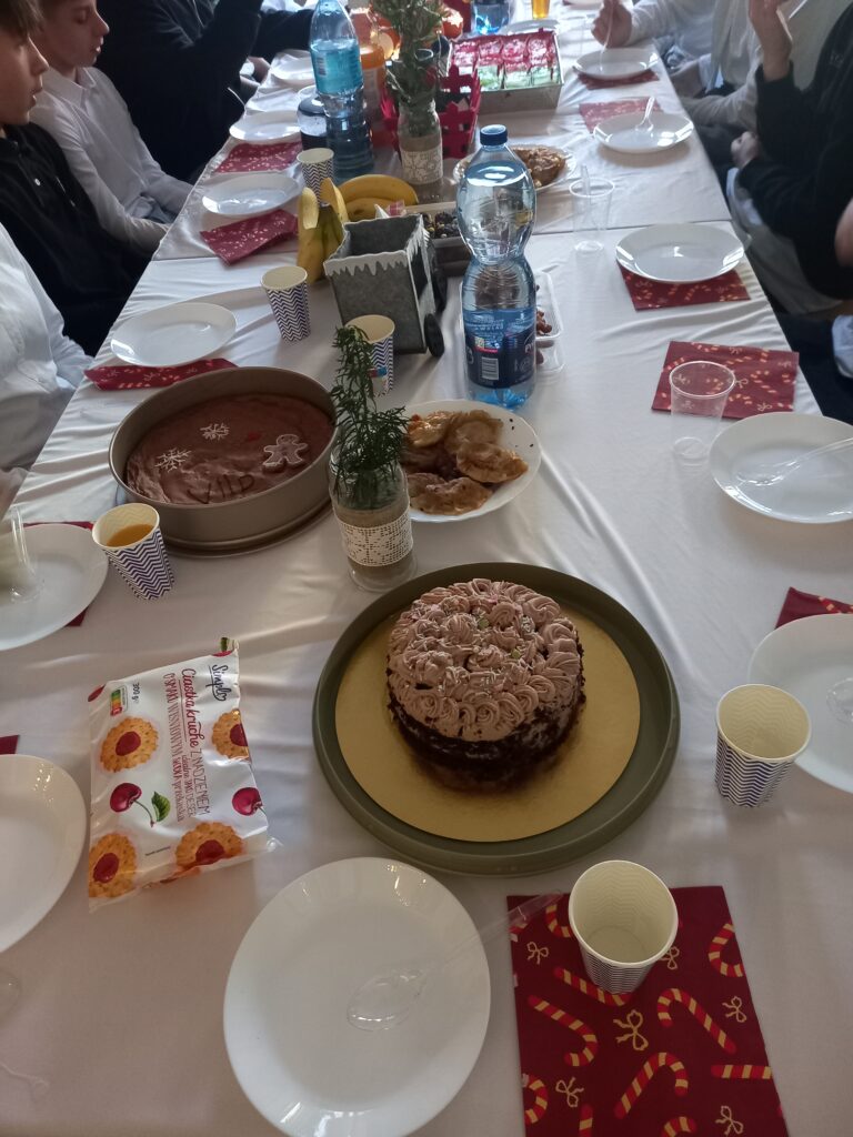 jedzenie i talerzyki rozłożone na ławkach przykryte białym obrusem