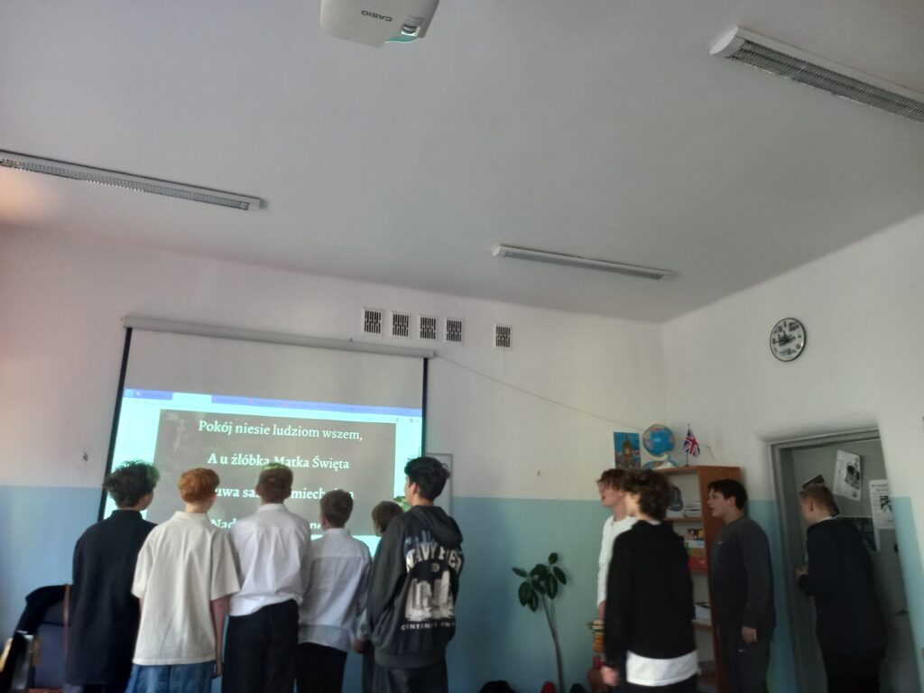 chłopcy stoją odwróceni do ekranu śpiewają kolędę