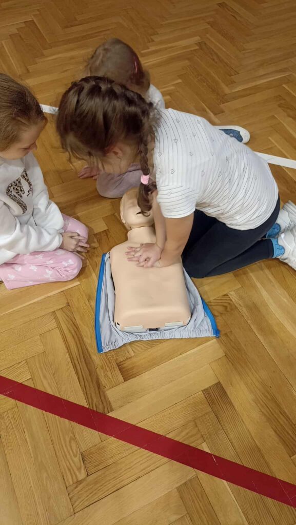 uczennica ćwiczy na fantomie pierwszą pomoc.