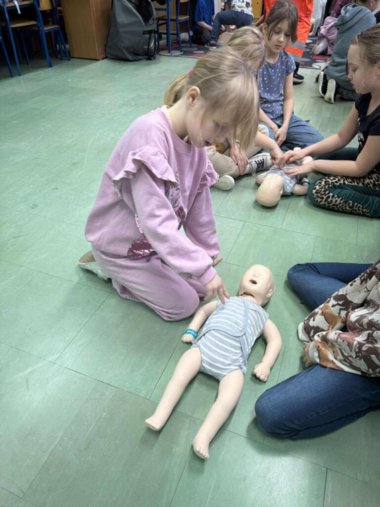 uczennica ćwiczy na fantomie pierwszą pomoc.