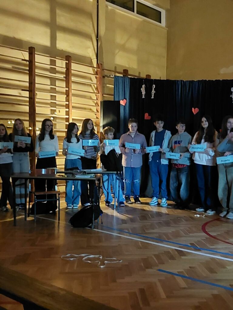 uczniowie podczas przedsytawienia, stoją jeden za drugim i trzymają kartki w rękach