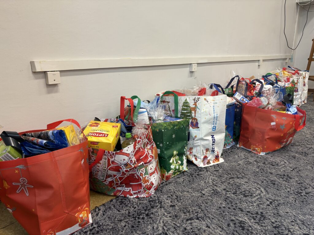 zdjęcie kolorowych reklamówek wypełnionych różnymi darami. Takimi jak herbata, ryż, kasza, słodycze, olej itp.