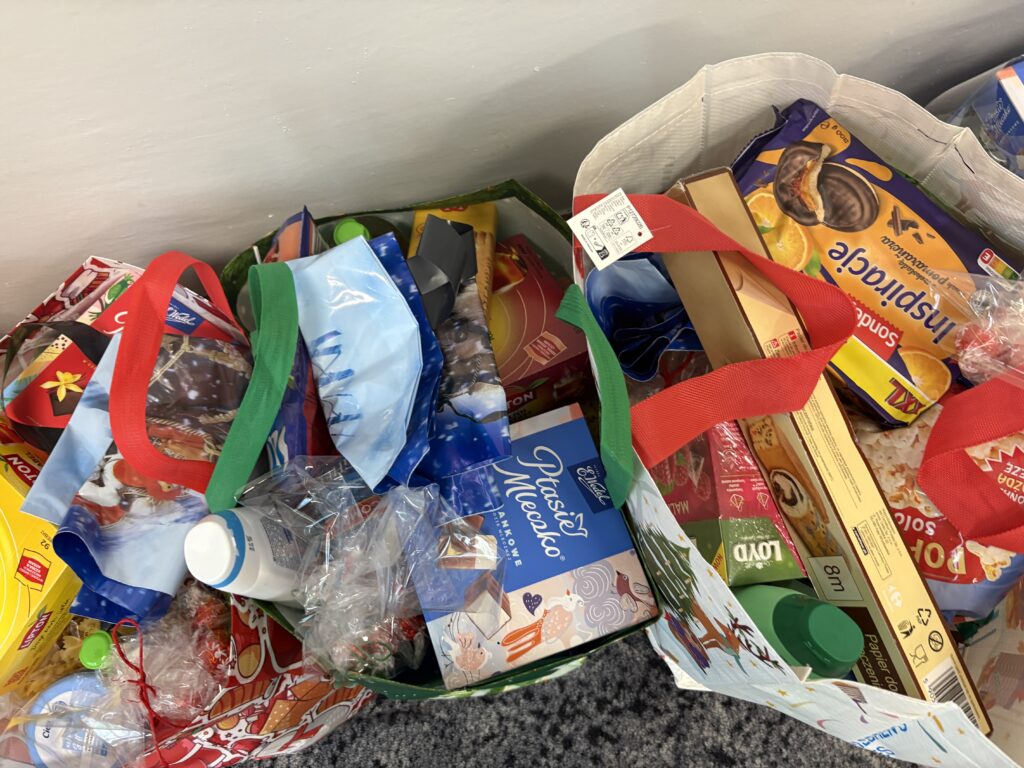 zdjęcie kolorowych reklamówek wypełnionych różnymi darami. Takimi jak herbata, ryż, kasza, słodycze, olej itp.