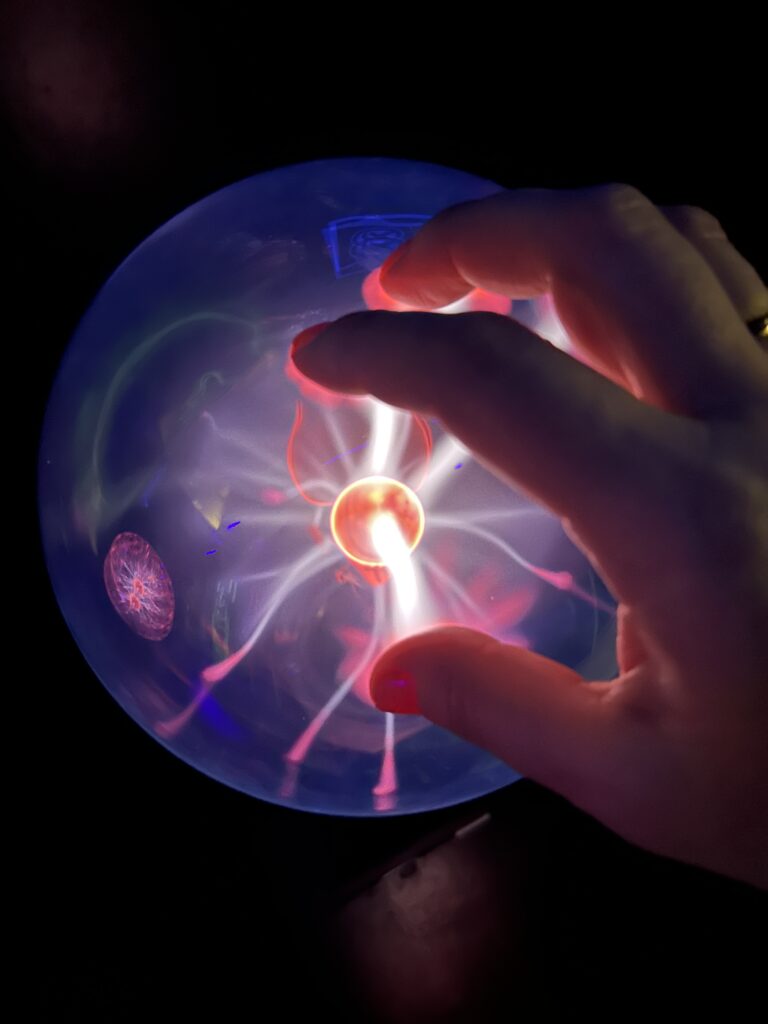 podświetlana kula, na niej położona dłoń, która przyciąga światło