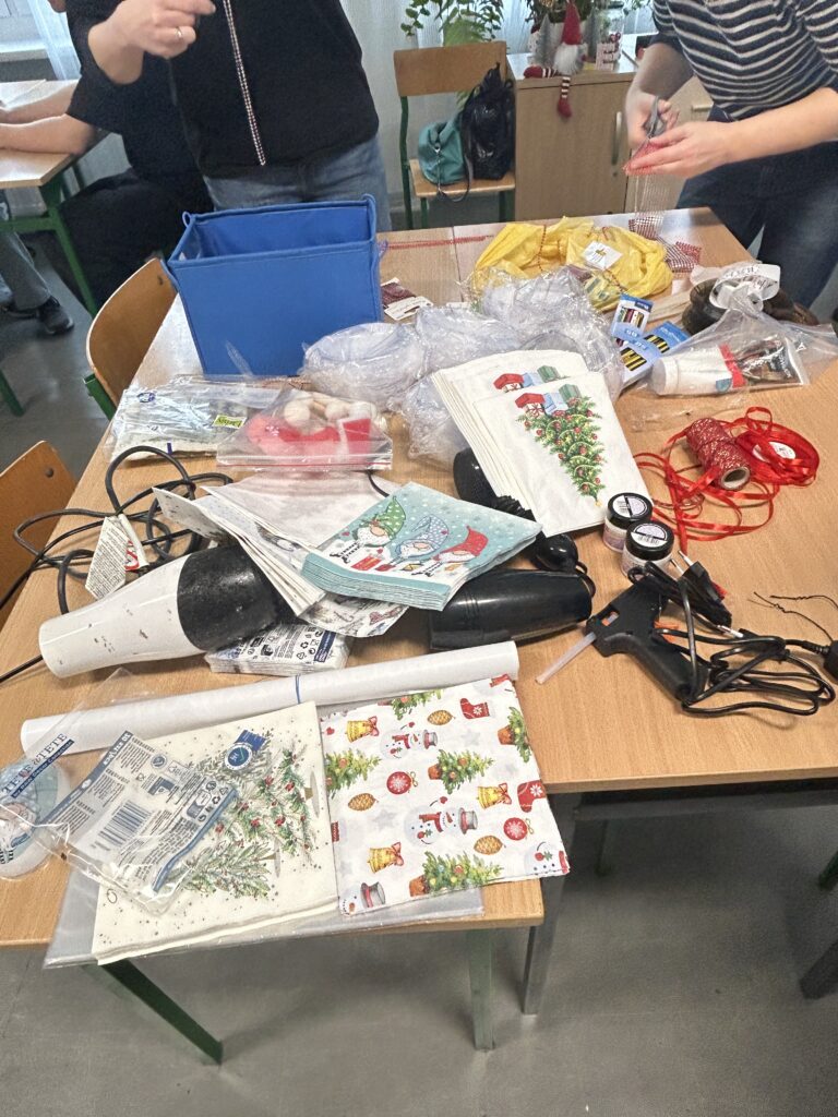 na ławkach leżą serwetki, suszarki, tasiemki czerwone, kleje, z których będą wykonywane ozdoby świąteczne