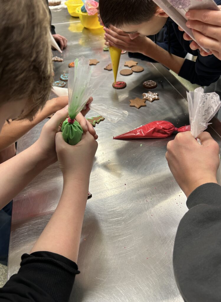 chłopcy dekorują swoje pierniczki. Wyciskają z torebek lukier