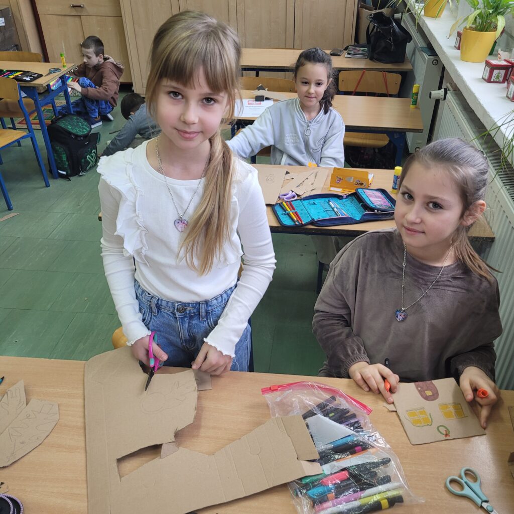 dziewczynki pracują przy ławkach. Wycinają, kolorują. 