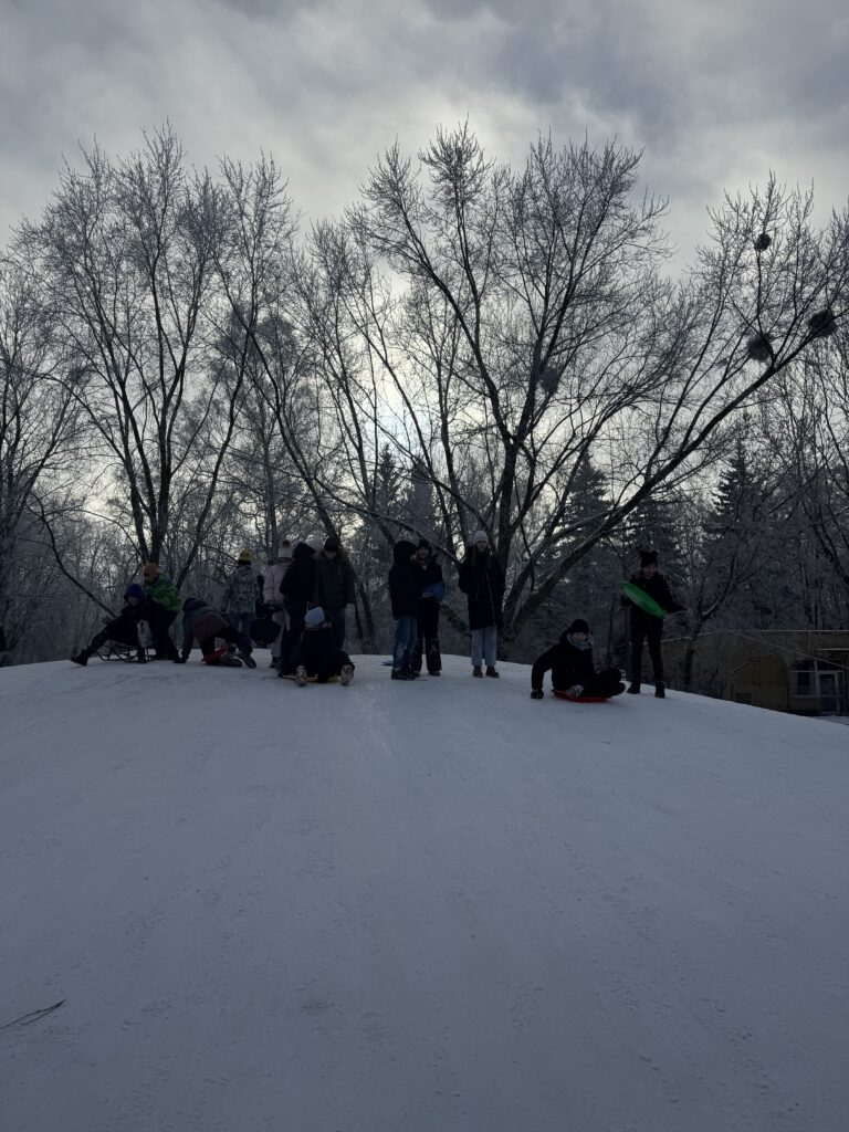 Uczniowie klasy 6b podczas wfu na śniegu zjeżdżają z górki.