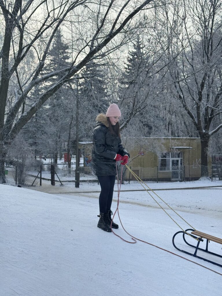Uczennica klasy 6b podczas wfu stoi na górce z sankami.