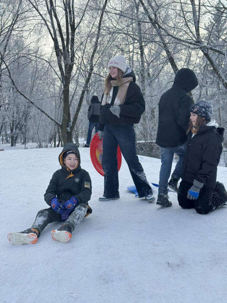 Uczniowie klasy 6b podczas wfu na śniegu zjeżdżają z górki.