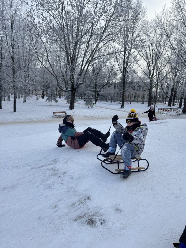 Uczniowie klasy 6b podczas wfu na śniegu zjeżdżają z górki.