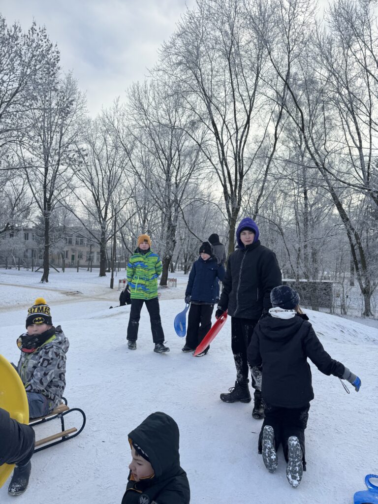 Uczniowie klasy 6b podczas wfu na śniegu zjeżdżają z górki.