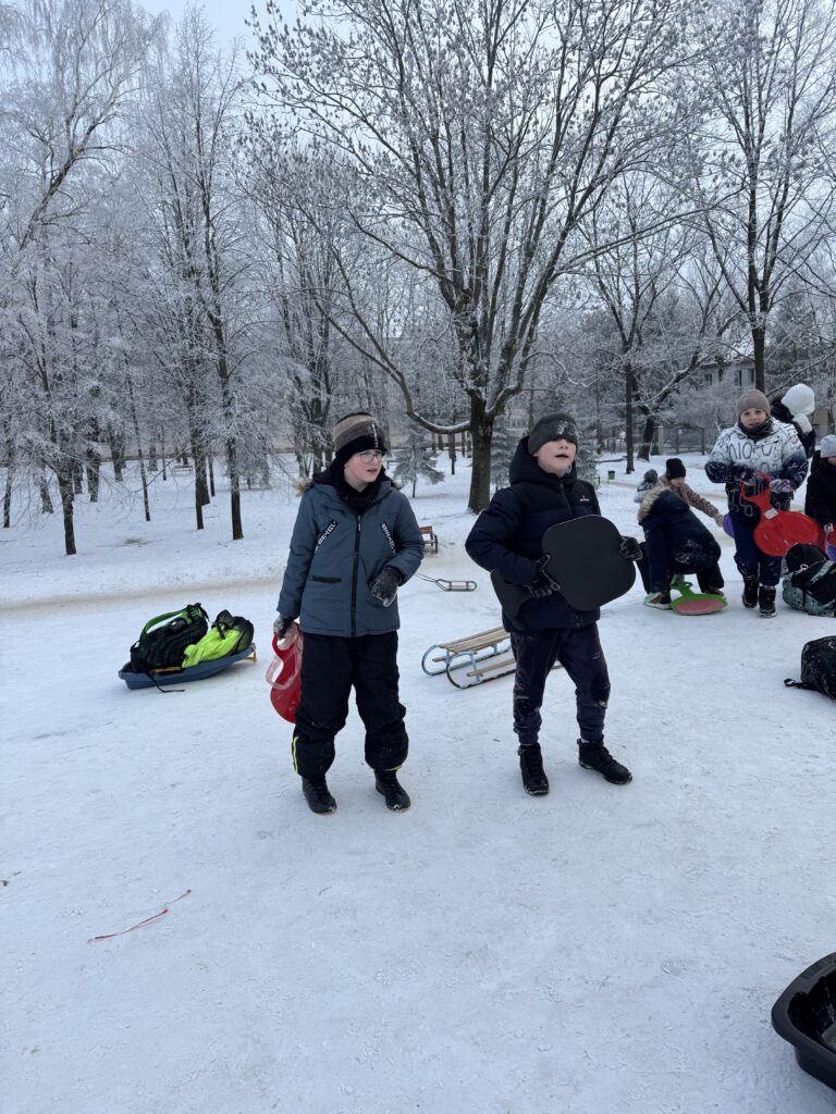 Uczniowie klasy 4b podczas wfu na śniegu zjeżdżają z górki.