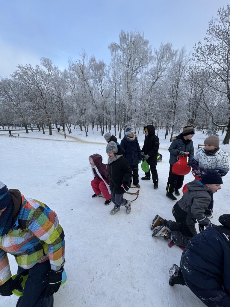 Uczniowie klasy 4b podczas wfu na śniegu zjeżdżają z górki.