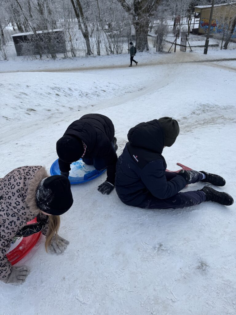 Uczniowie klasy 4b podczas wfu na śniegu zjeżdżają z górki.