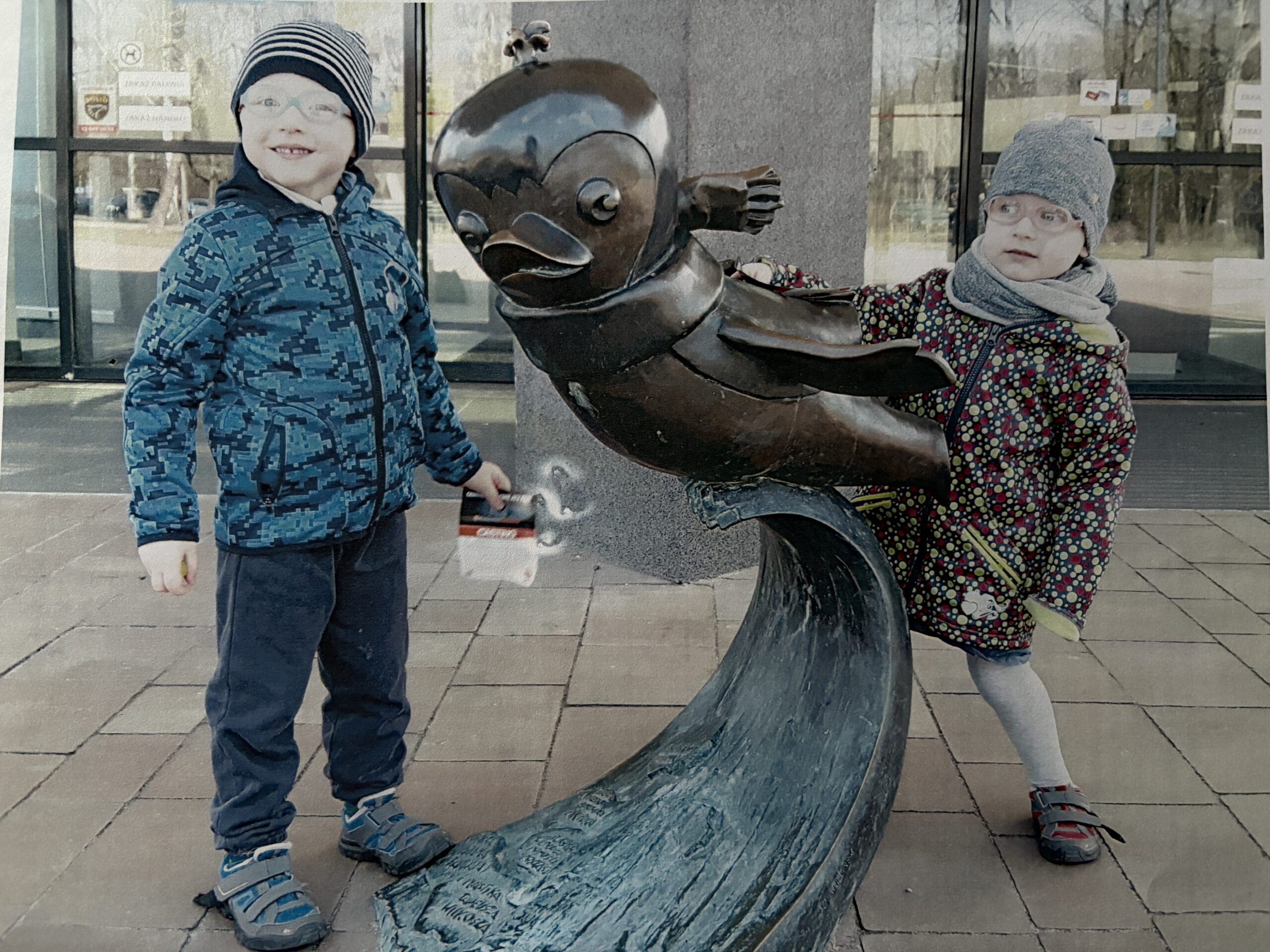 dzieci na zdjęciu stoją przy pomniku ptaszka