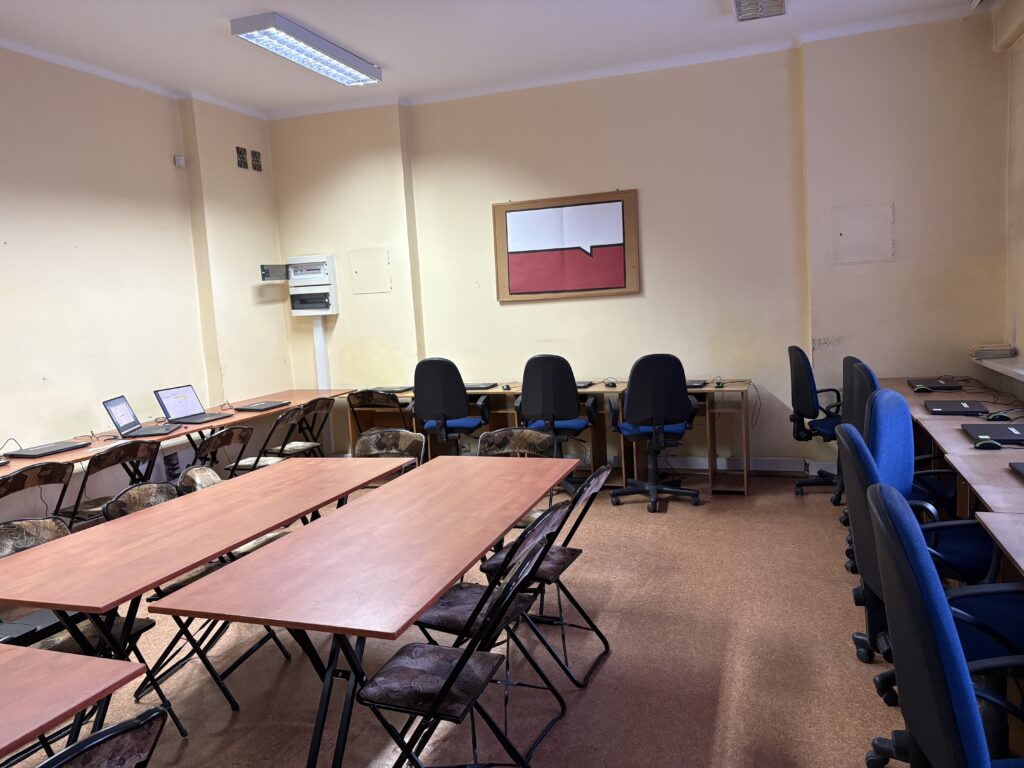 Zdjęcie przedstawia fragment klasy z krzesłami, ławkami i nowymi laptopami.