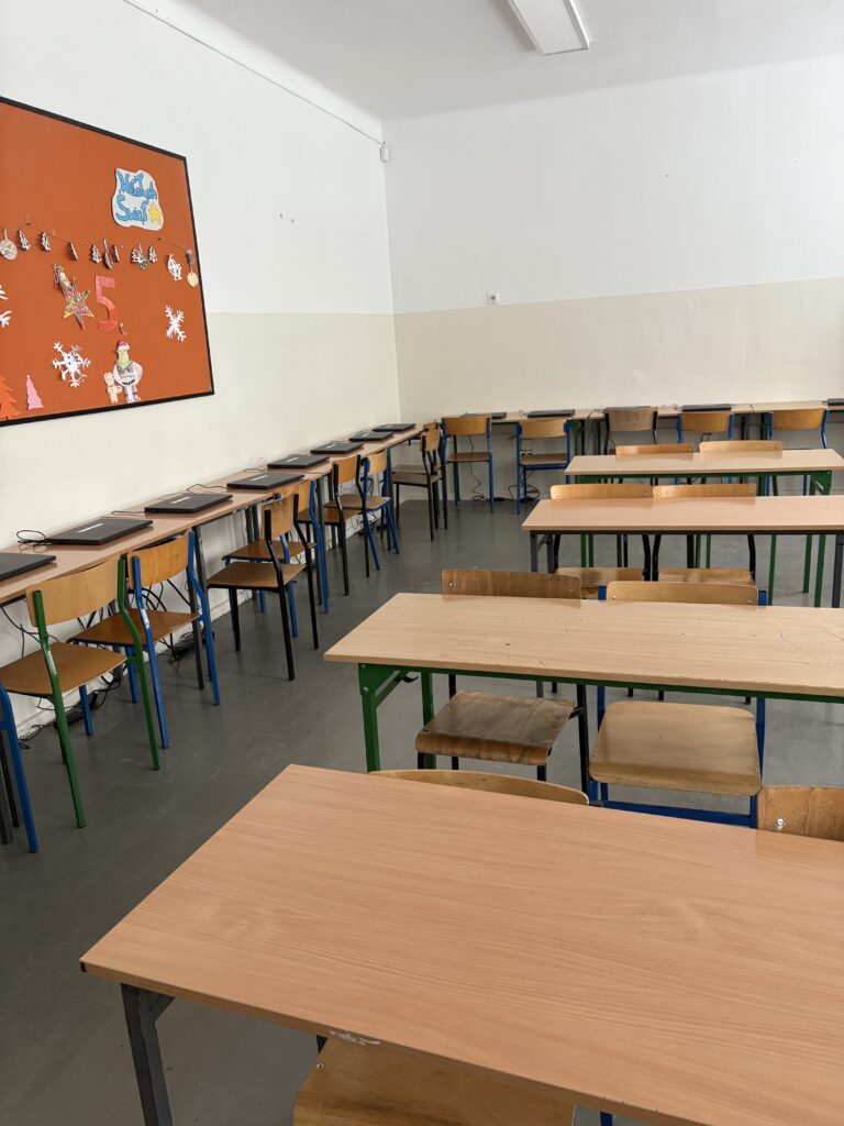 Zdjęcie przedstawia fragment klasy z krzesłami, ławkami i nowymi laptopami.