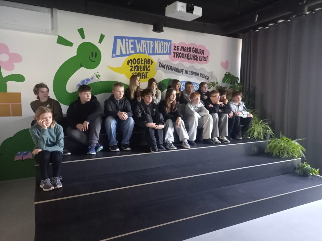 zdjęcie grupowe klasy siedzącej na schodach w muzeum 