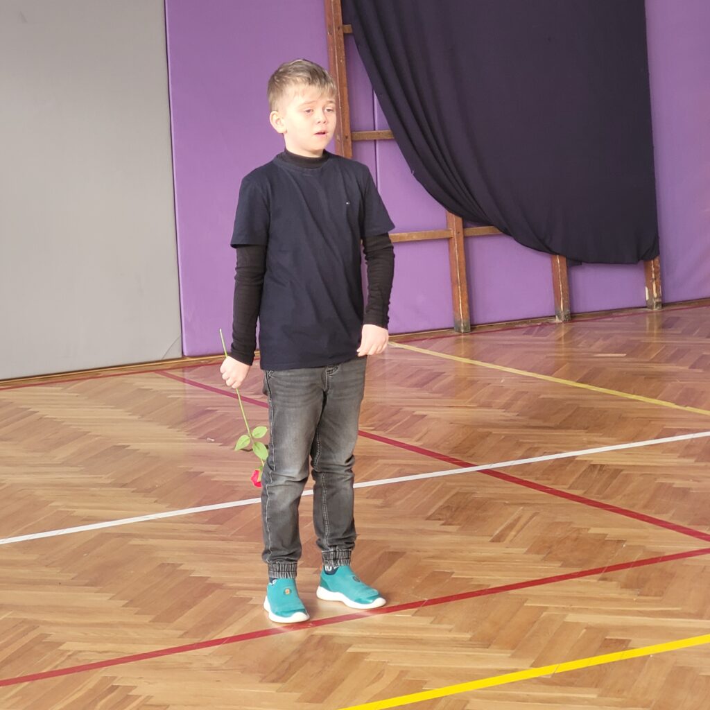 uczeń śpiewa i trzyma róże 
