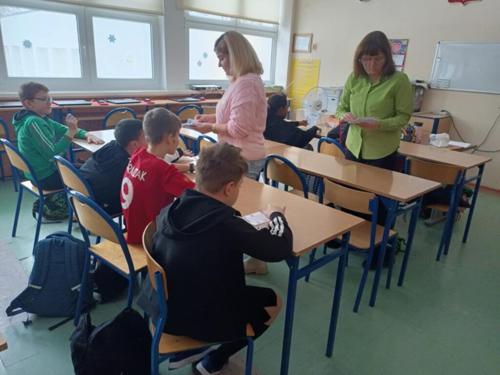 nauczycielki dwie rozdają uczniom ulotki