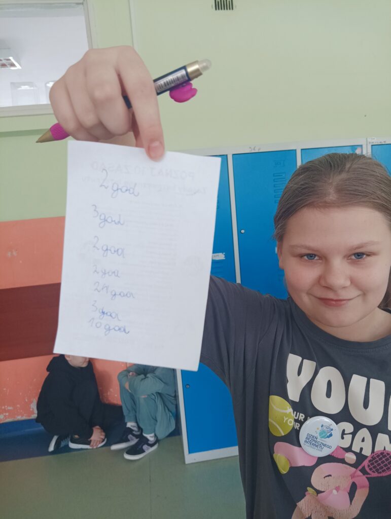 dziewczynka pokazuje kartkę z napisami ile dzieci spędzają czasu na komputerze