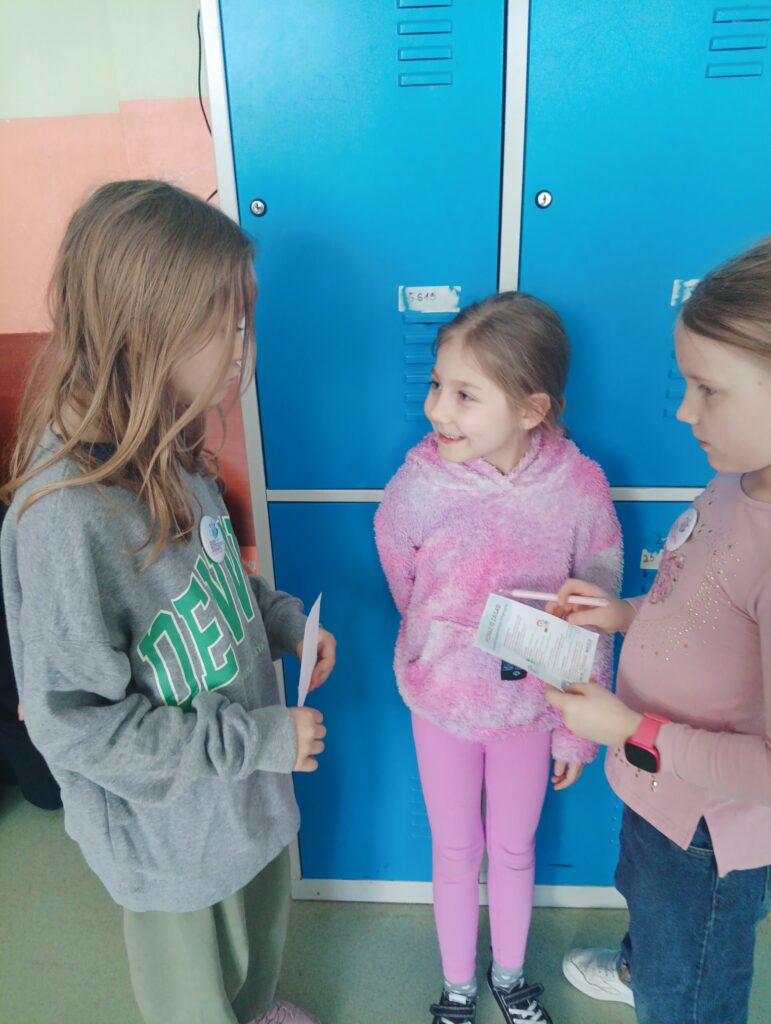 uczniowie rozmawiają trzymając ulotki