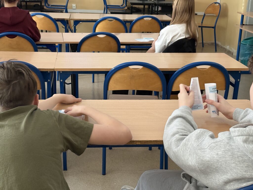 zdjęcie dzieci od tyłu, trzymają ulotki