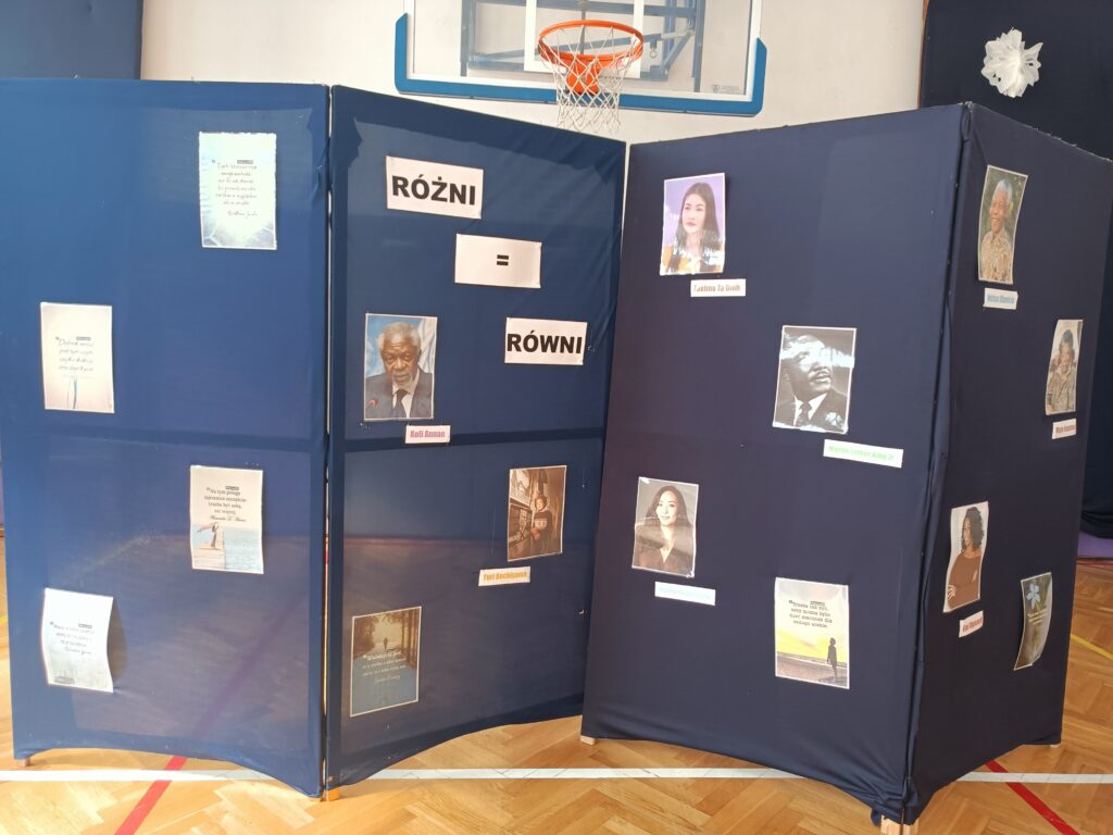 zdjęcie granatowej ściany ekspozycji na której widnieją zdjęcia ludzi głoszących tolerancję na świecie 