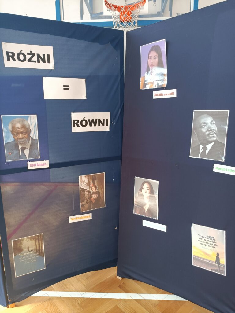 zdjęcie granatowej ściany ekspozycji na której widnieją zdjęcia ludzi głoszących tolerancję na świecie 