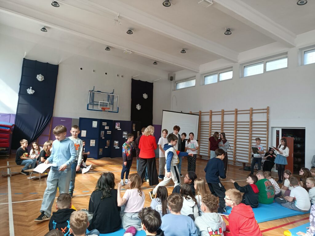 widać stojące dzieci i panią Dyrektor, Na dole siedzą dzieci.