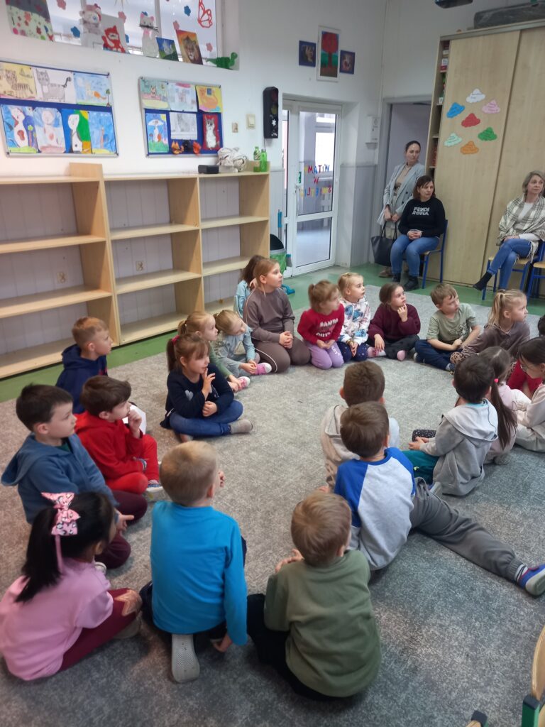 przedszkolaki siedzą na dywanie w sali