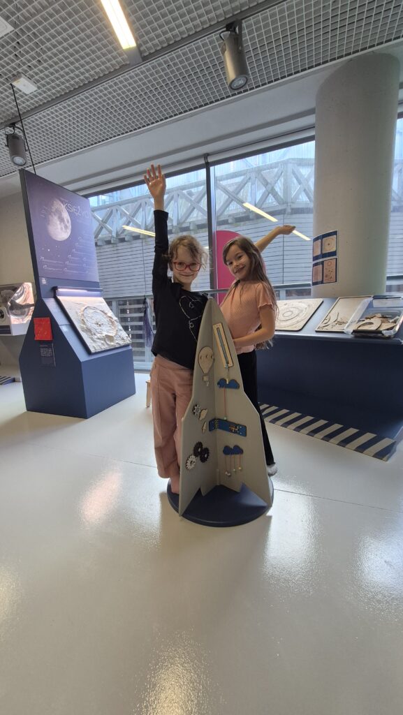 Uczennice przeprowadzają eksperymenty w EC1, stoją przy makiecie rakiety.