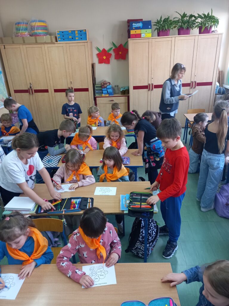 przedszkolaki siedzą w ławkach szkolnych