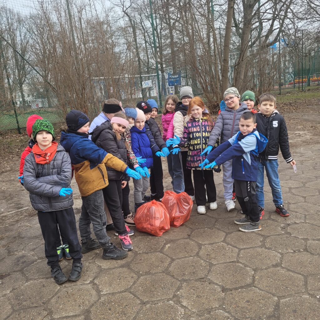 Na zdjęciu widać uczniów naszej szkoły biorących udział w akcji proekologicznej, którzy prezentują zebrane przez siebie worki ze śmieciami.