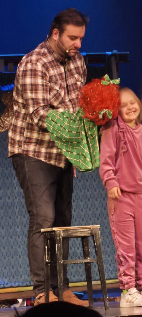 aktor i dziecko na scenie, dziewczynka uśmiecha się dotykana przez kukiełkę 