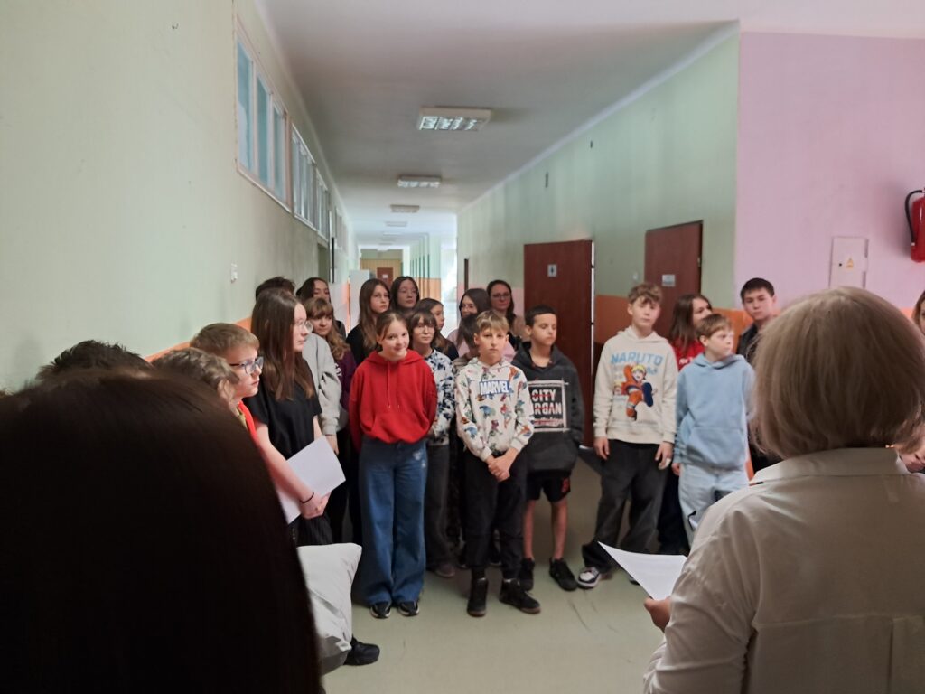 Uczniowie i nauczyciele zebrani podczas otwarcia nowej przestrzeni w szkole. Dyrektor zapoznaje uczniów z regulaminem korzystania z Pokoju.