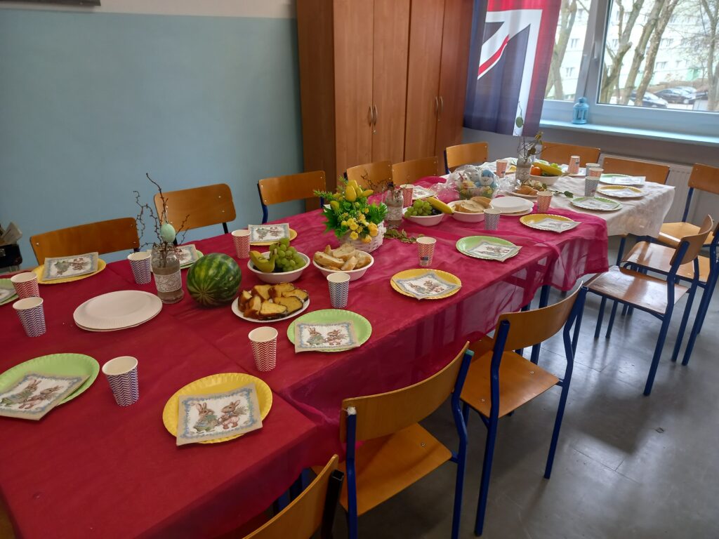 stoły nakryte czerwonymi obrusami, kolorowymi talerzykami kubeczkami i płożone jedzenie