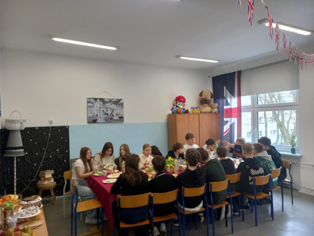 dzieci siedzą przy przystrojonych obrusami i jedzeniem pokrytych stołach