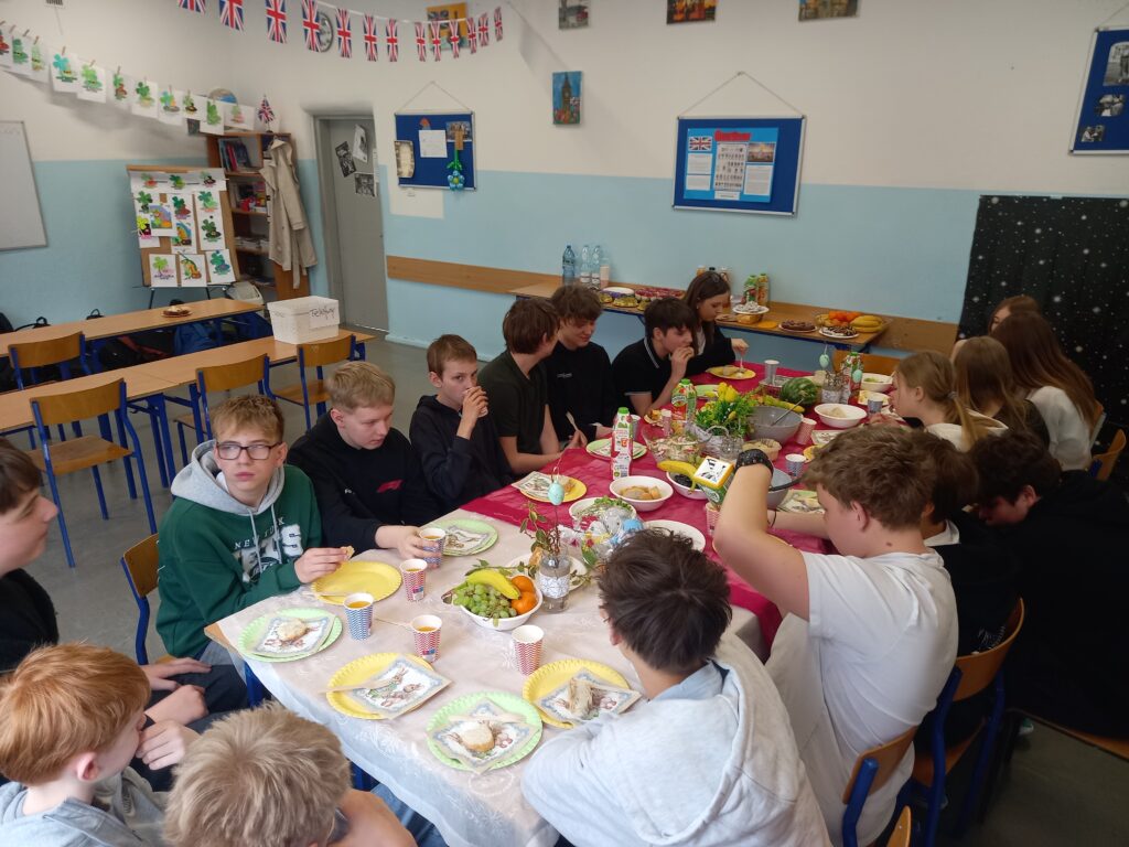 dzieci siedzą przy przystrojonych obrusami i jedzeniem pokrytych stołach