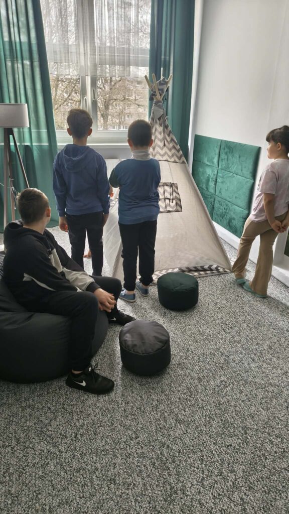 Uczniowie poznają wyposażenie Pokoju Wyciszeń: namiot, pufy, lampę.